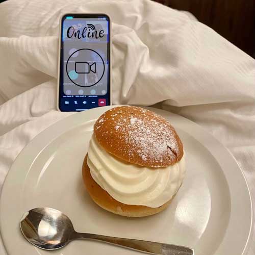 En semla på tallrik och en mobil i en säng